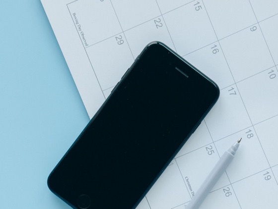 A phone resting on a calendar, representing an online booking flow