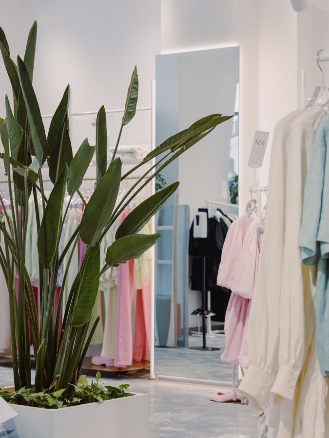 A bright boutique clothing store with racks of pastel garments
